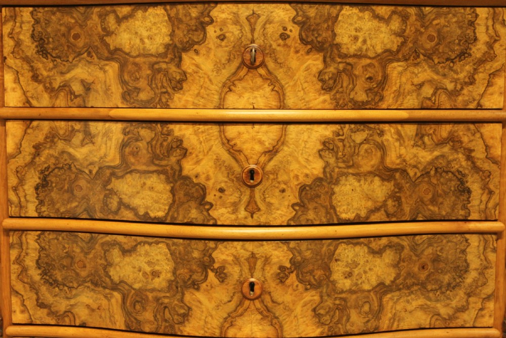 A Neo-Rococo Swedish chest of drawers featuring a serpentine front, highly figured burr walnut veneer, carved foliate corner pilasters, and four full-width drawers. View VI