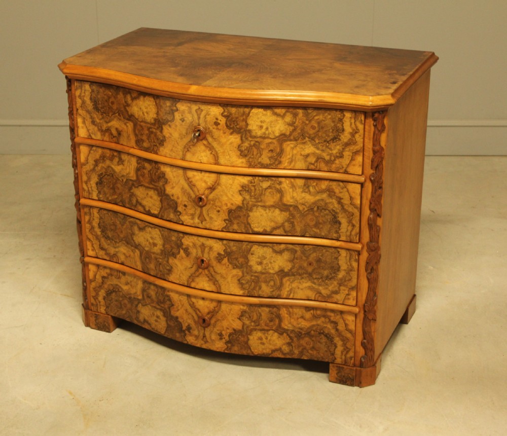A Neo-Rococo Swedish chest of drawers featuring a serpentine front, highly figured burr walnut veneer, carved foliate corner pilasters, and four full-width drawers. View VII