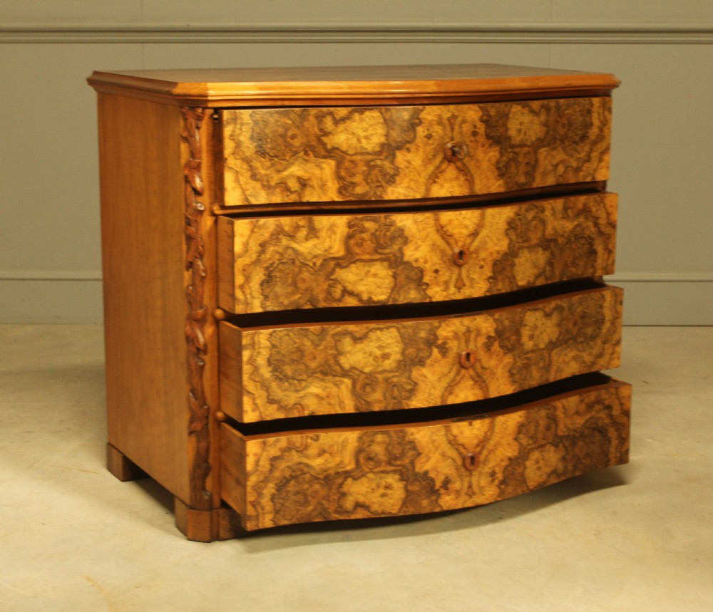 A Neo-Rococo Swedish chest of drawers featuring a serpentine front, highly figured burr walnut veneer, carved foliate corner pilasters, and four full-width drawers. View VIII