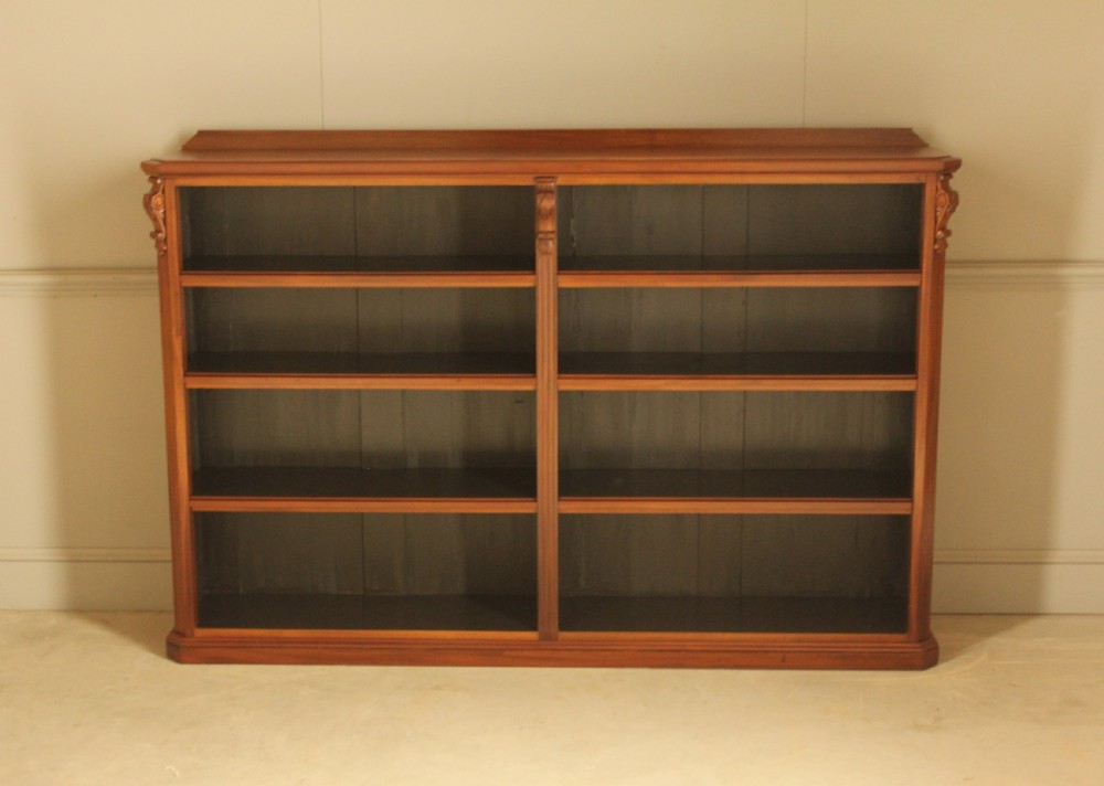 A Victorian warm brown mahogany open bookcase with two sections of shelves, carved corbel details, and a plinth base. View II