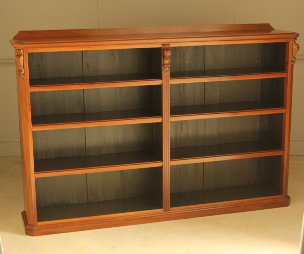 A Victorian warm brown mahogany open bookcase with two sections of shelves, carved corbel details, and a plinth base. View III