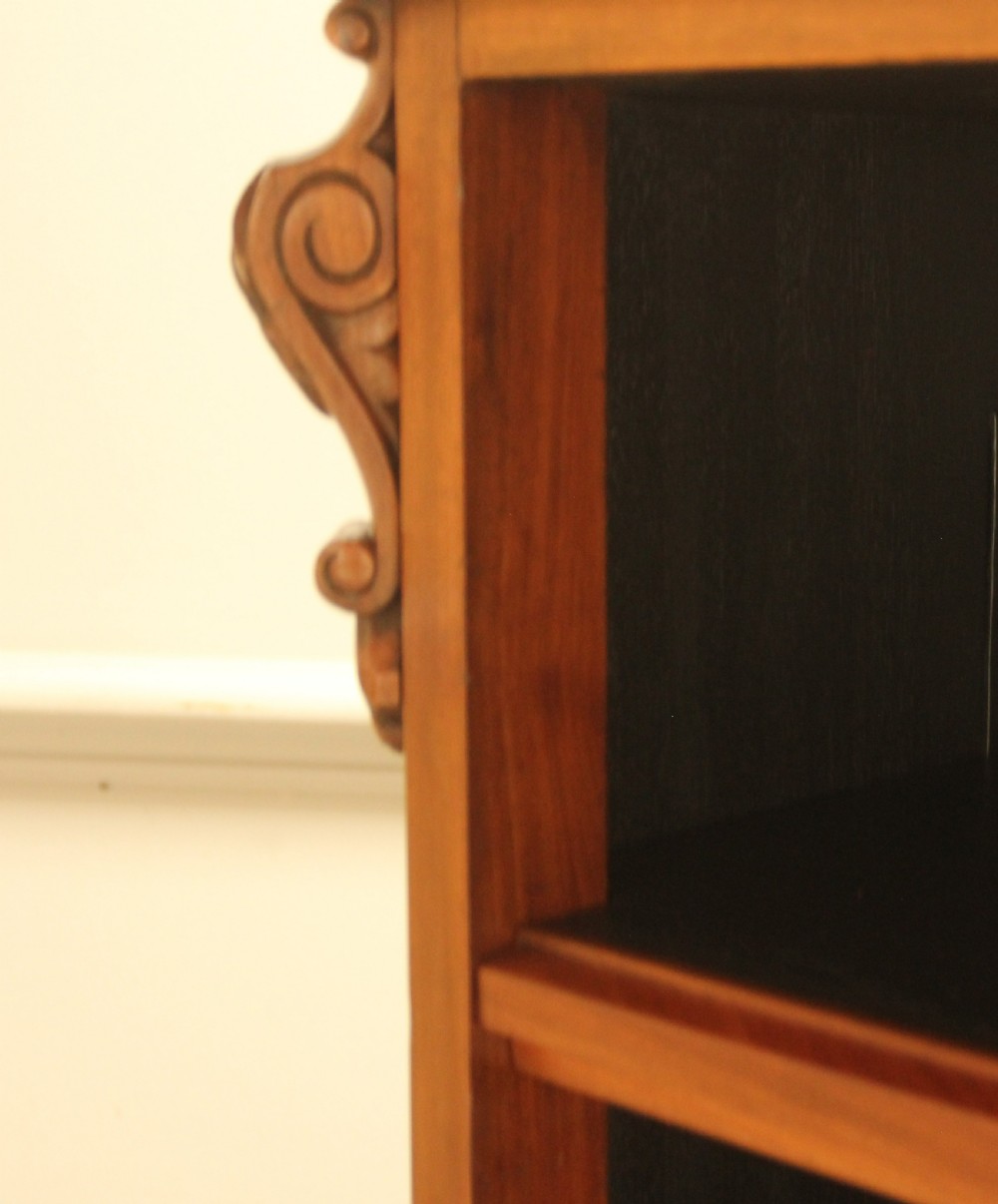 A Victorian warm brown mahogany open bookcase with two sections of shelves, carved corbel details, and a plinth base. View V