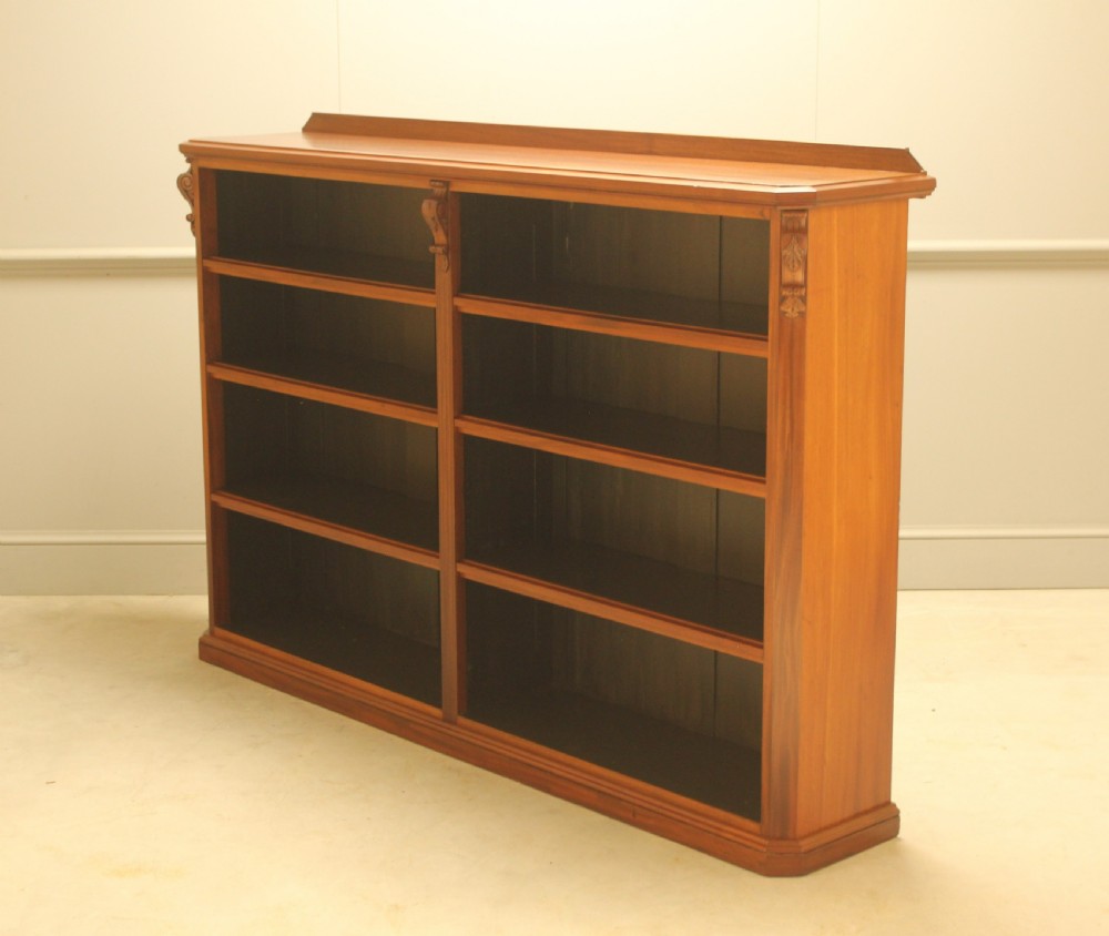 A Victorian warm brown mahogany open bookcase with two sections of shelves, carved corbel details, and a plinth base. View VI