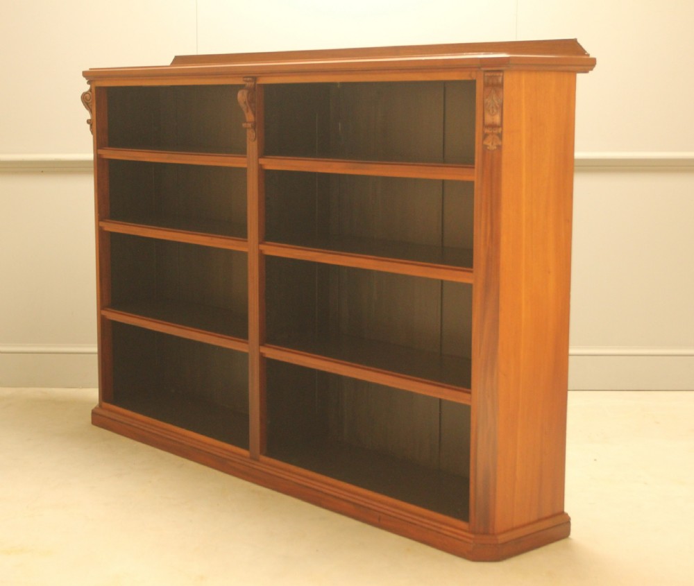 A Victorian warm brown mahogany open bookcase with two sections of shelves, carved corbel details, and a plinth base. View VII