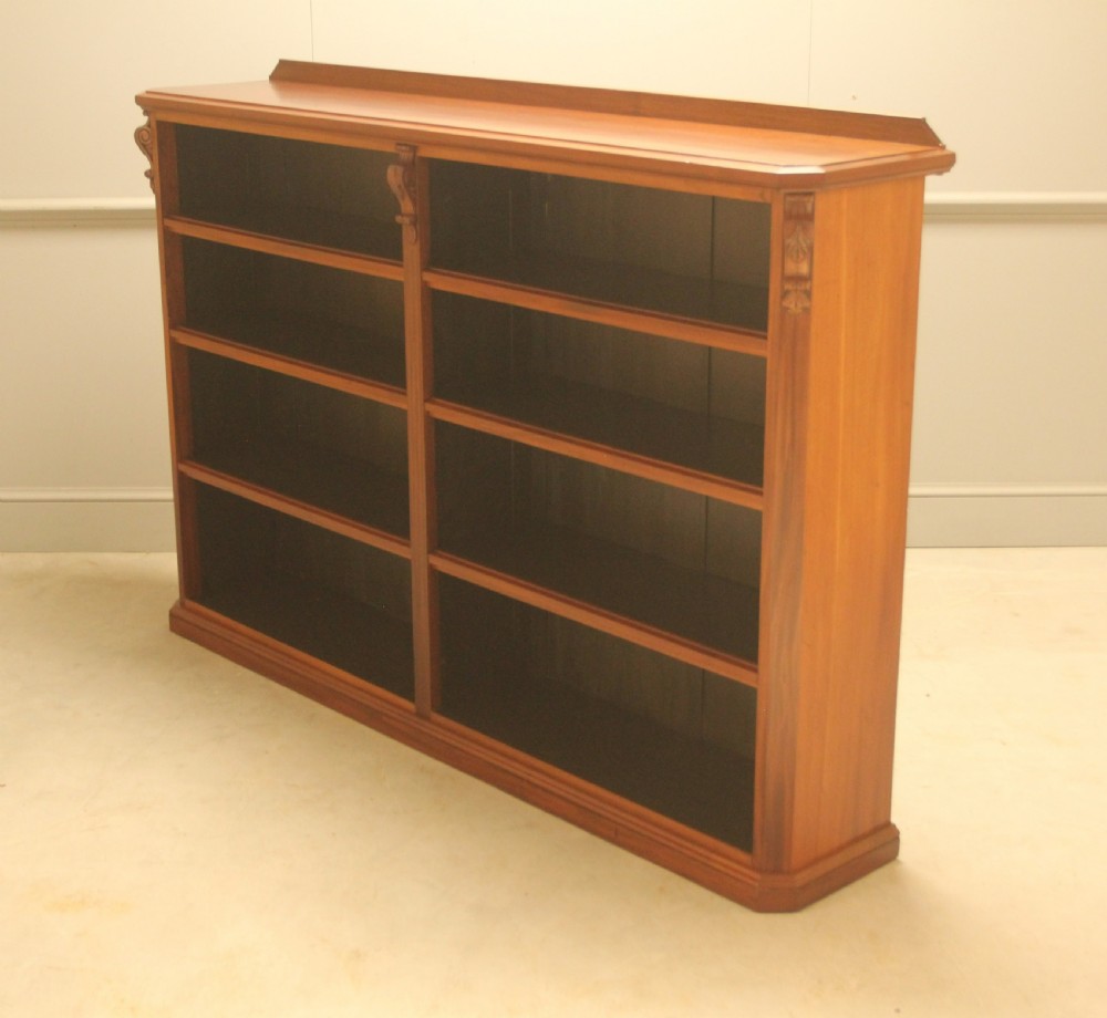 A Victorian warm brown mahogany open bookcase with two sections of shelves, carved corbel details, and a plinth base. View VIII