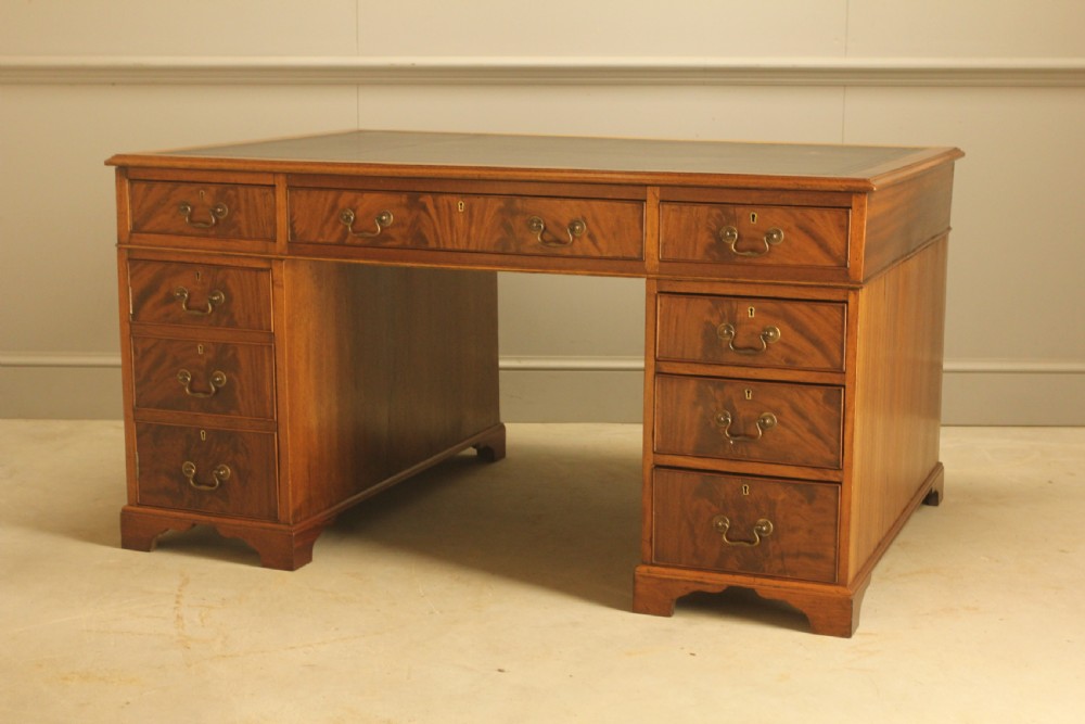 A Victorian mahogany partners desk featuring a brown leather writing inset, twin pedestals with nine drawers, and brass swan-neck handles. View V
