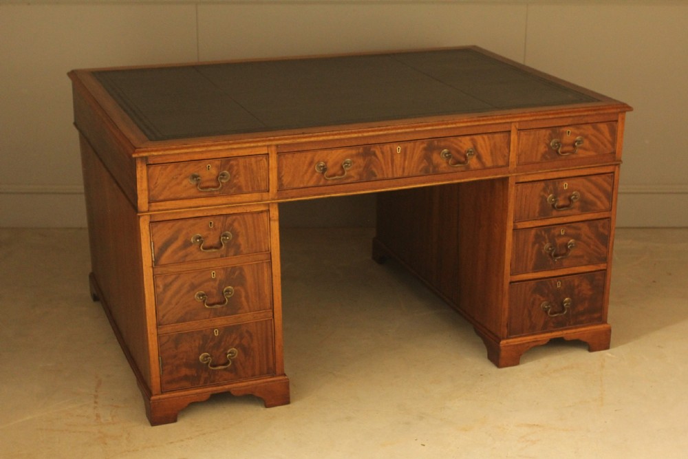 A Victorian mahogany partners desk featuring a brown leather writing inset, twin pedestals with nine drawers, and brass swan-neck handles. View VI