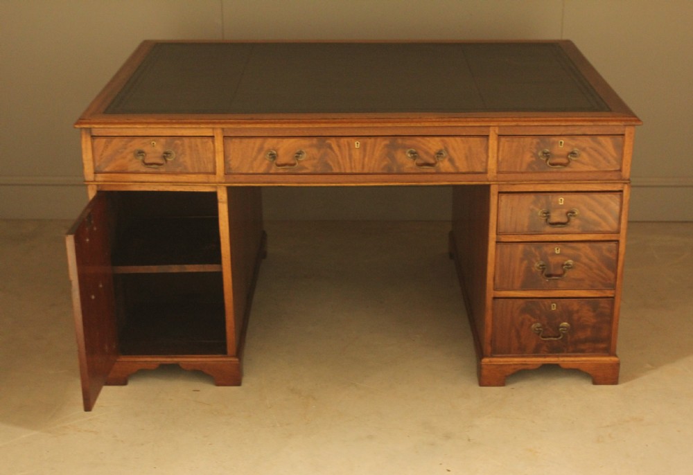 A Victorian mahogany partners desk featuring a brown leather writing inset, twin pedestals with nine drawers, and brass swan-neck handles. View VIII