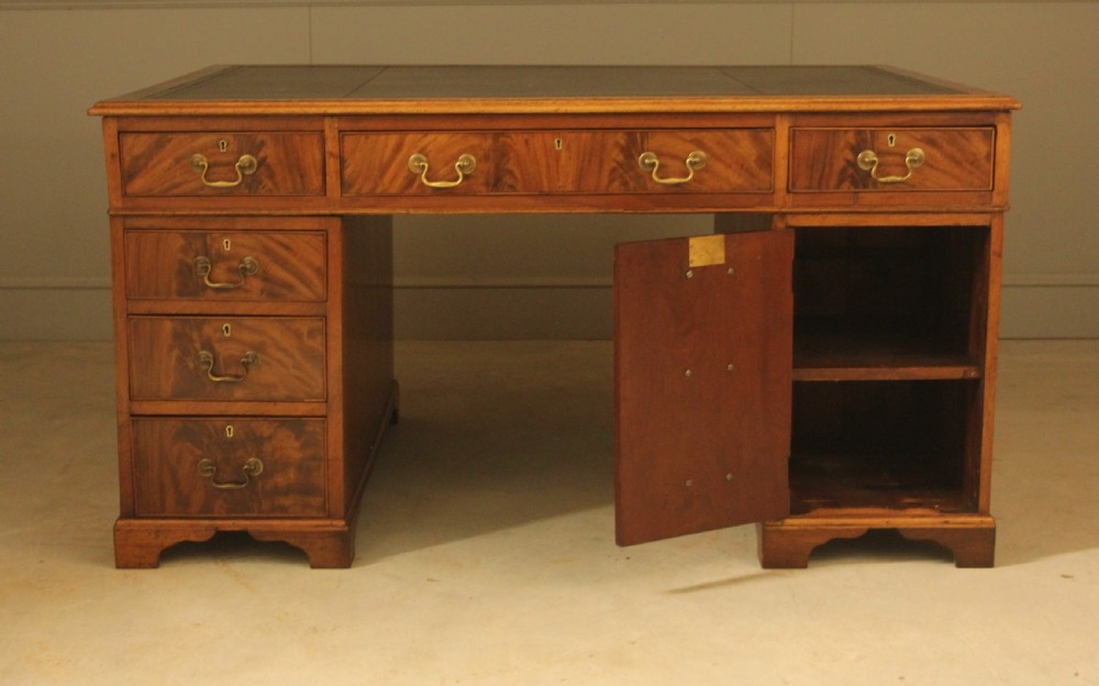 A Victorian mahogany partners desk featuring a brown leather writing inset, twin pedestals with nine drawers, and brass swan-neck handles. View X