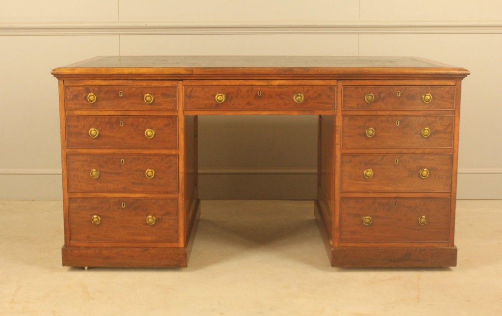 A 19th-century mahogany partners desk featuring a dark leather writing inset top, nine drawers on the front with brass ring handles, and twin pedestal bases.