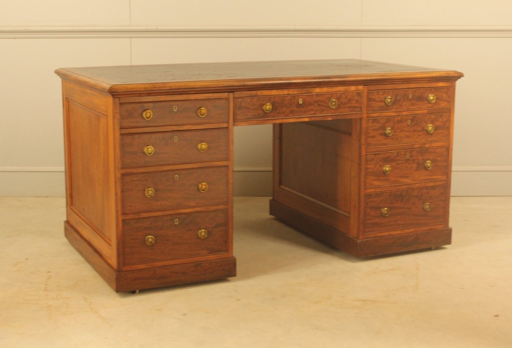 A 19th-century mahogany partners desk featuring a dark leather writing inset top, nine drawers on the front with brass ring handles, and twin pedestal bases. View V