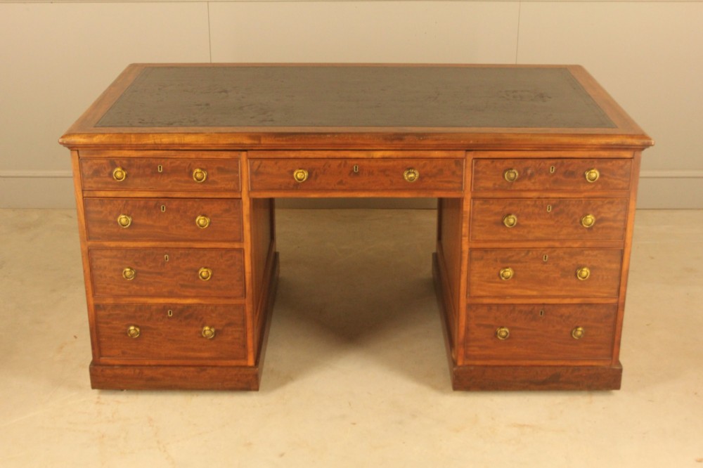 A 19th-century mahogany partners desk featuring a dark leather writing inset top, nine drawers on the front with brass ring handles, and twin pedestal bases. View VII