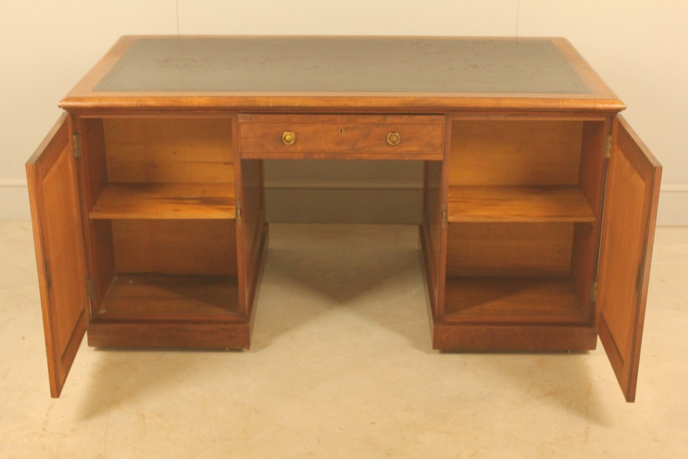 A 19th-century mahogany partners desk featuring a dark leather writing inset top, nine drawers on the front with brass ring handles, and twin pedestal bases. View IX
