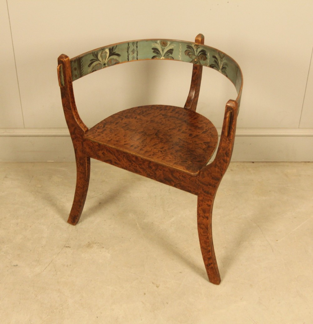 An early 20th-century Norwegian wooden chair with a curved backrest decorated with hand-painted green floral motifs and a faux-grained finish.