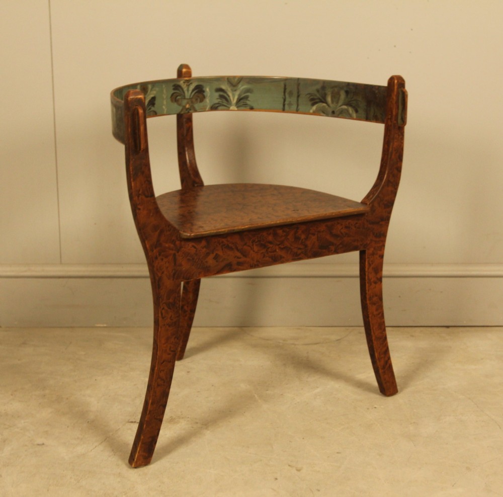An early 20th-century Norwegian wooden chair with a curved backrest decorated with hand-painted green floral motifs and a faux-grained finish. View X