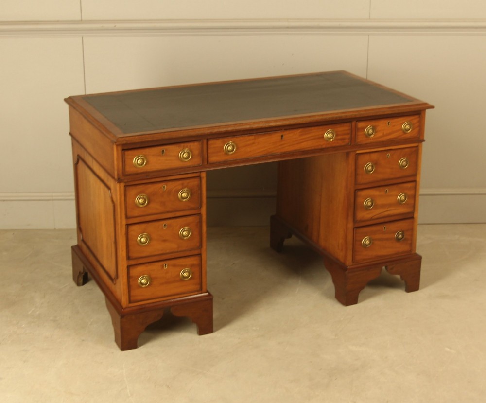 Victorian mahogany pedestal writing desk featuring nine drawers with brass ring pulls and bracket feet. View V