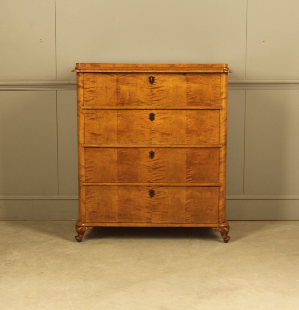 A 19th-century Swedish chest of drawers crafted from flame birch veneer with four horizontal drawers, central dark escutcheons, and short carved bracket feet.