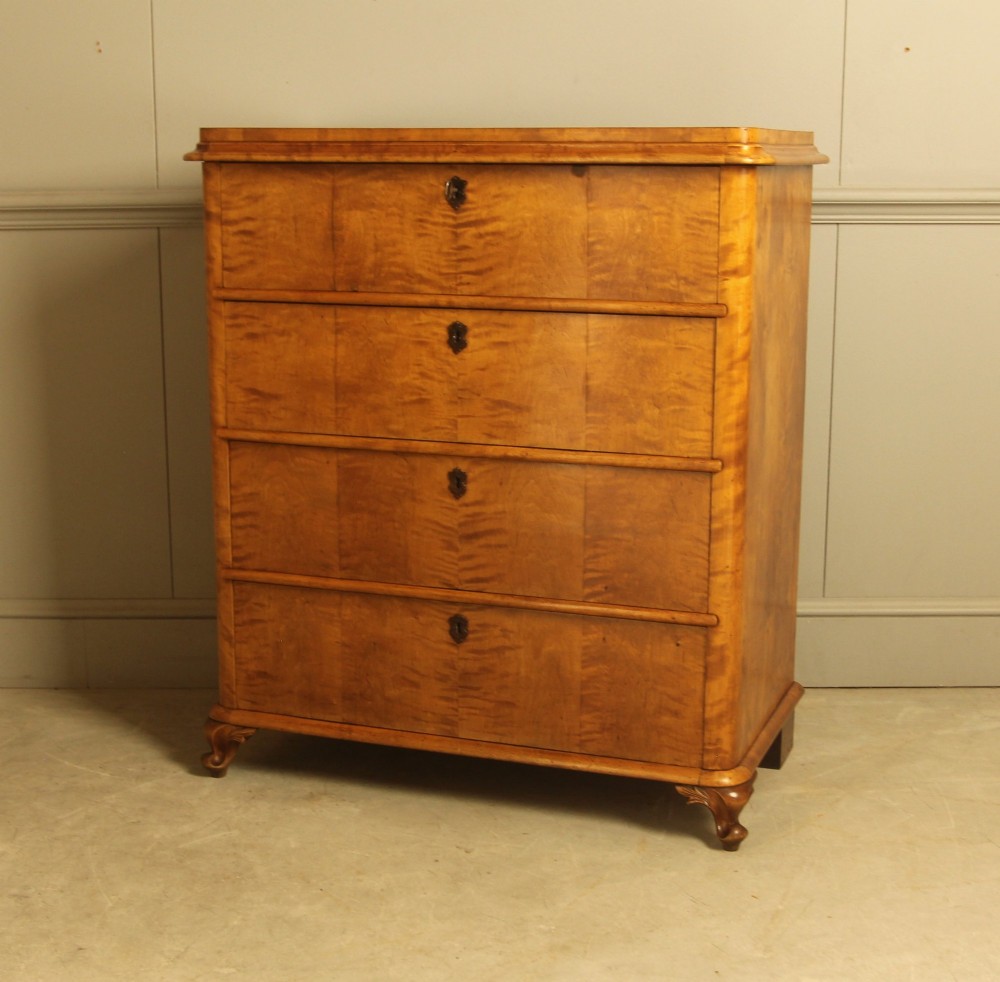 A 19th-century Swedish chest of drawers crafted from flame birch veneer with four horizontal drawers, central dark escutcheons, and short carved bracket feet. View IV