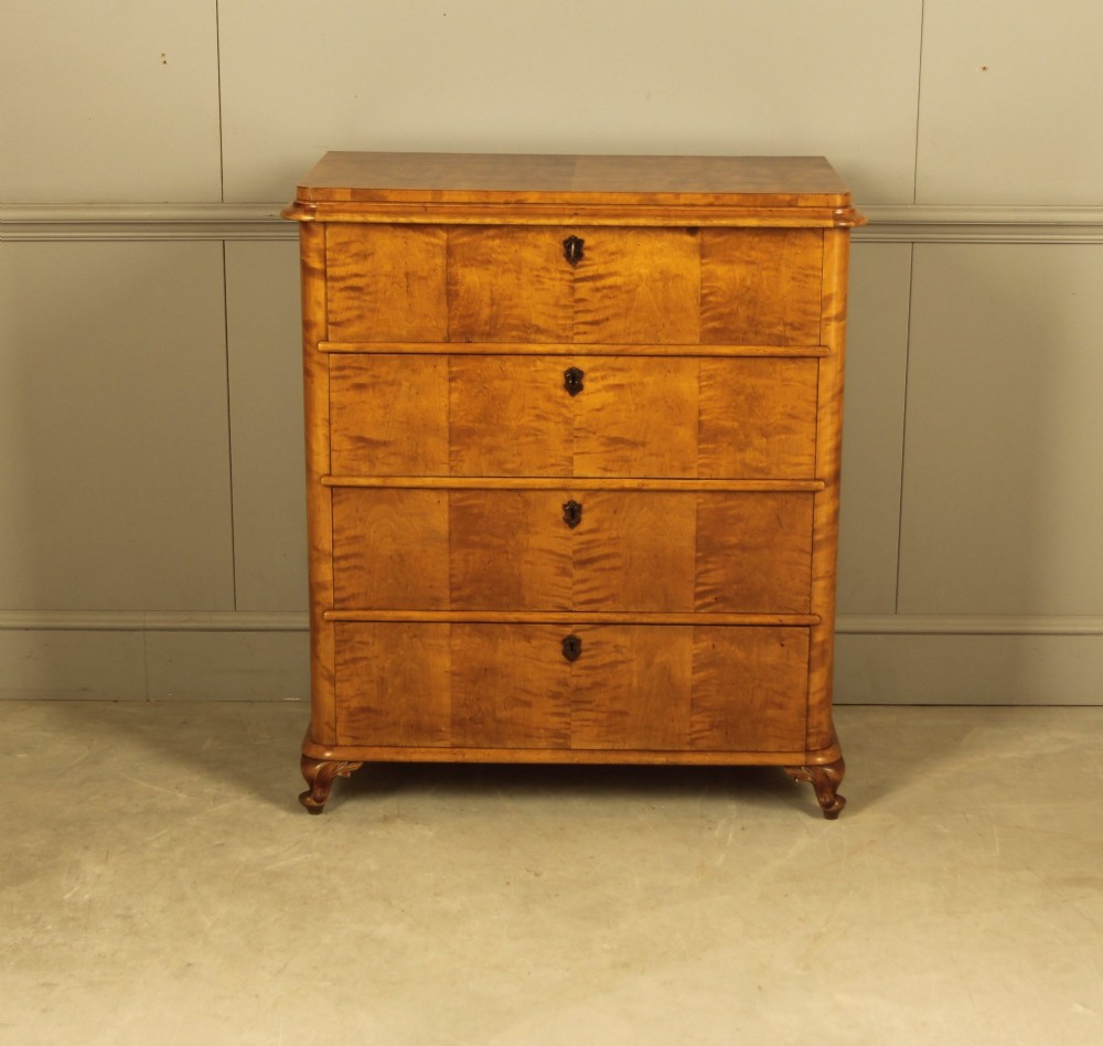 A 19th-century Swedish chest of drawers crafted from flame birch veneer with four horizontal drawers, central dark escutcheons, and short carved bracket feet. View V