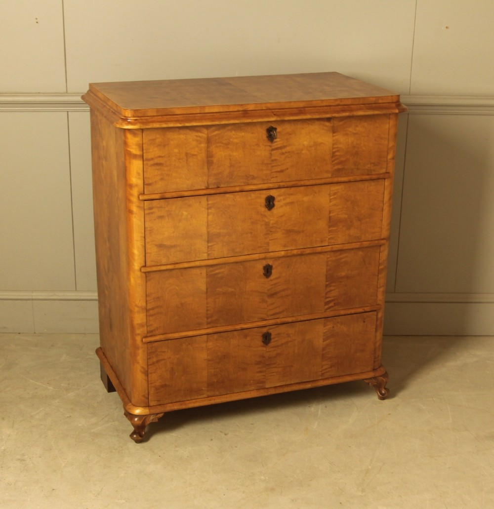 A 19th-century Swedish chest of drawers crafted from flame birch veneer with four horizontal drawers, central dark escutcheons, and short carved bracket feet. View VI