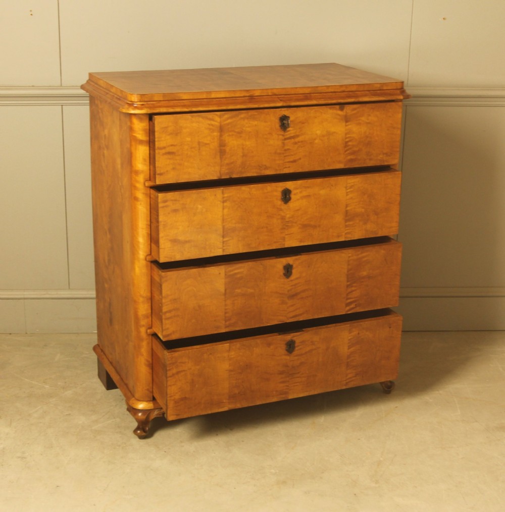 A 19th-century Swedish chest of drawers crafted from flame birch veneer with four horizontal drawers, central dark escutcheons, and short carved bracket feet. View VII