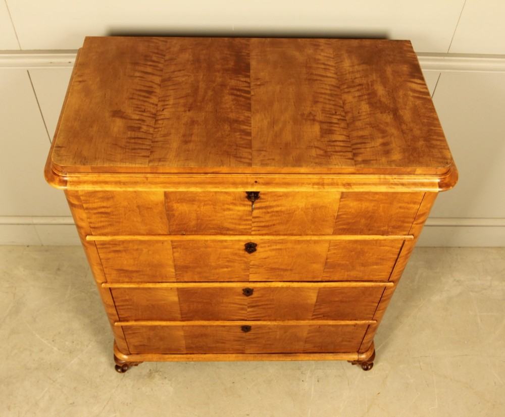 A 19th-century Swedish chest of drawers crafted from flame birch veneer with four horizontal drawers, central dark escutcheons, and short carved bracket feet. View IX