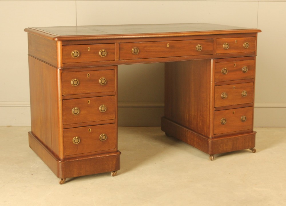 A Victorian mahogany pedestal desk featuring nine drawers with brass ring pulls and an inset leather writing top.