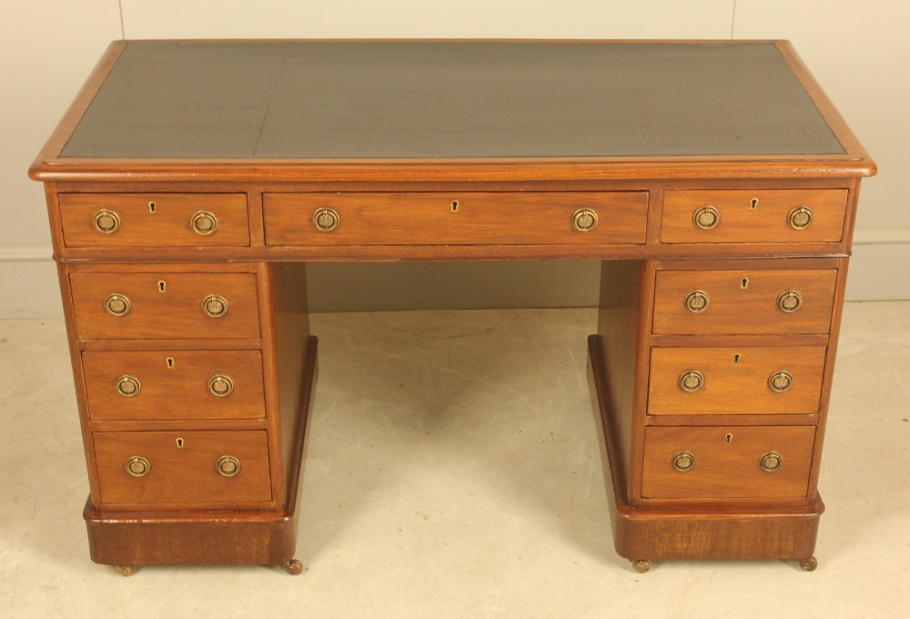 A Victorian mahogany pedestal desk featuring nine drawers with brass ring pulls and an inset leather writing top. View V