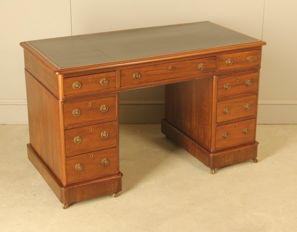 A Victorian mahogany pedestal desk featuring nine drawers with brass ring pulls and an inset leather writing top. View VI