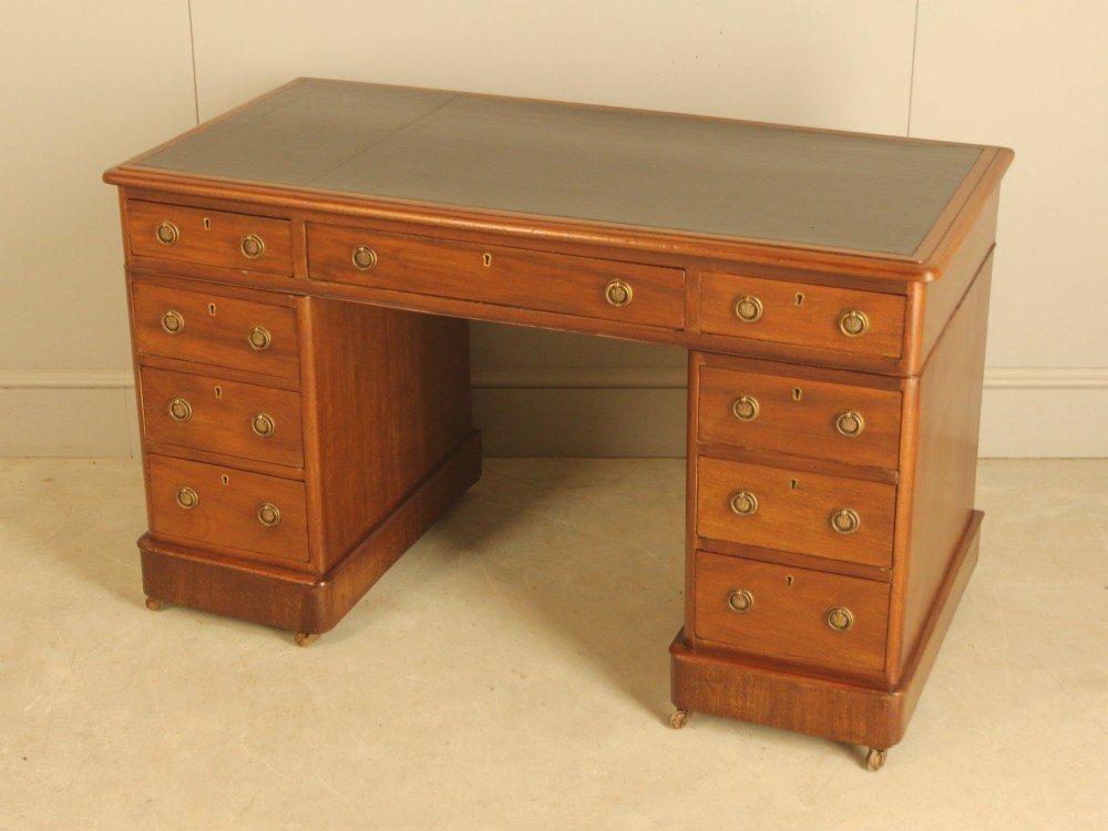 A Victorian mahogany pedestal desk featuring nine drawers with brass ring pulls and an inset leather writing top. View VIII