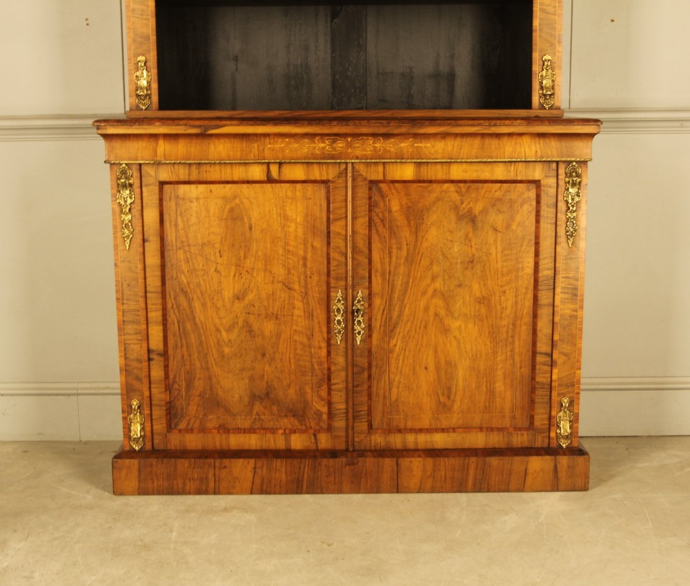 A 19th-century Victorian walnut bookcase featuring an open two-shelf upper section above a two-door lower cupboard with gilt metal mounts and inlaid detailing. View II