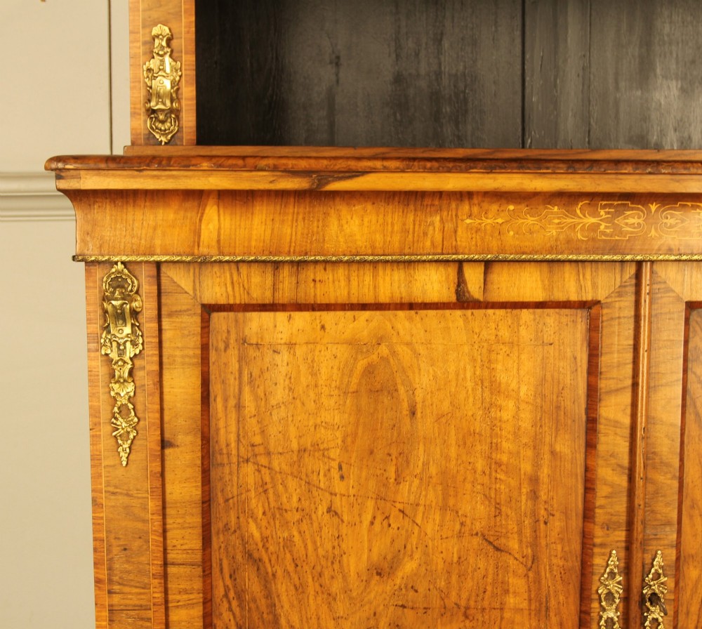 A 19th-century Victorian walnut bookcase featuring an open two-shelf upper section above a two-door lower cupboard with gilt metal mounts and inlaid detailing. View VII