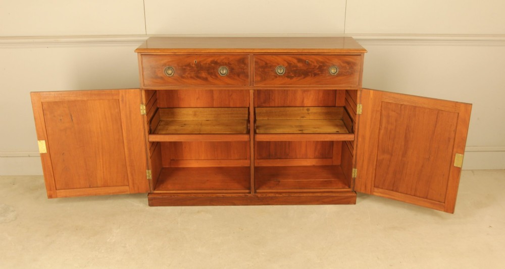 An Edwardian curl mahogany two-door sideboard featuring two top drawers with brass ring handles and panelled cupboard doors on a plinth base. View VIII