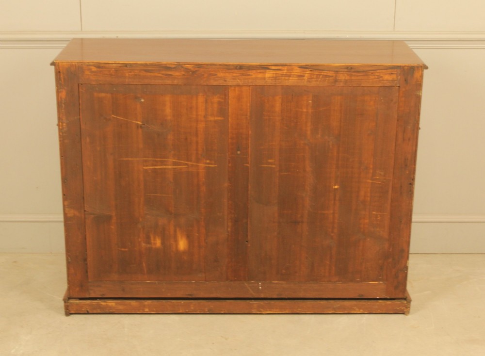 An Edwardian curl mahogany two-door sideboard featuring two top drawers with brass ring handles and panelled cupboard doors on a plinth base. View IX