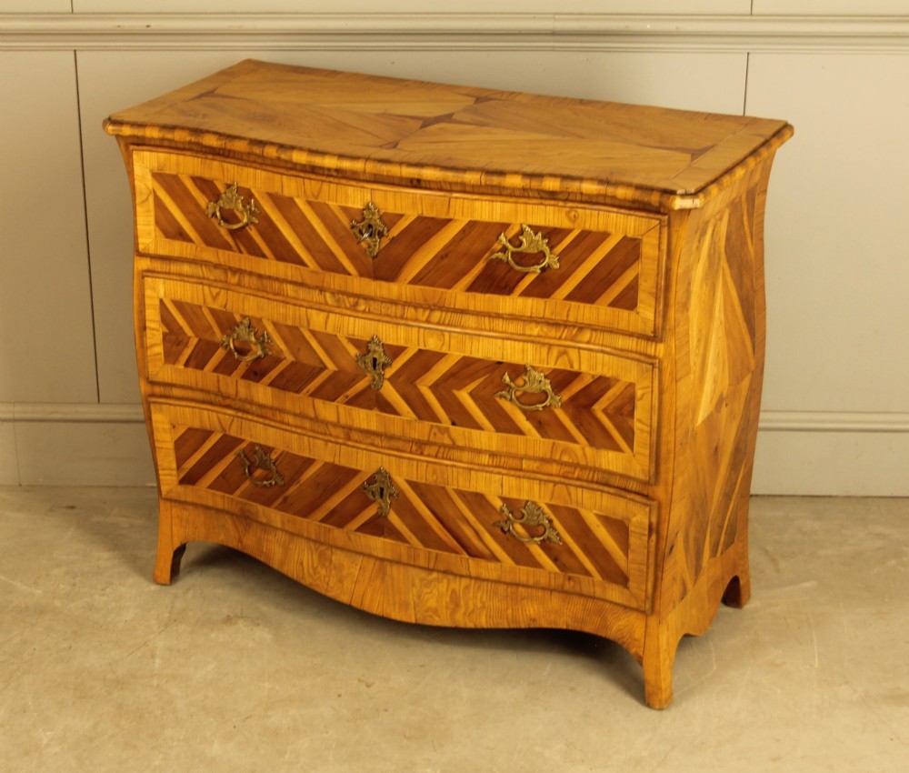 An 18th-century Swedish Rococo bombe chest of drawers featuring geometric chevron parquetry inlays, curved sides, three long drawers, and cast brass hardware. View VII