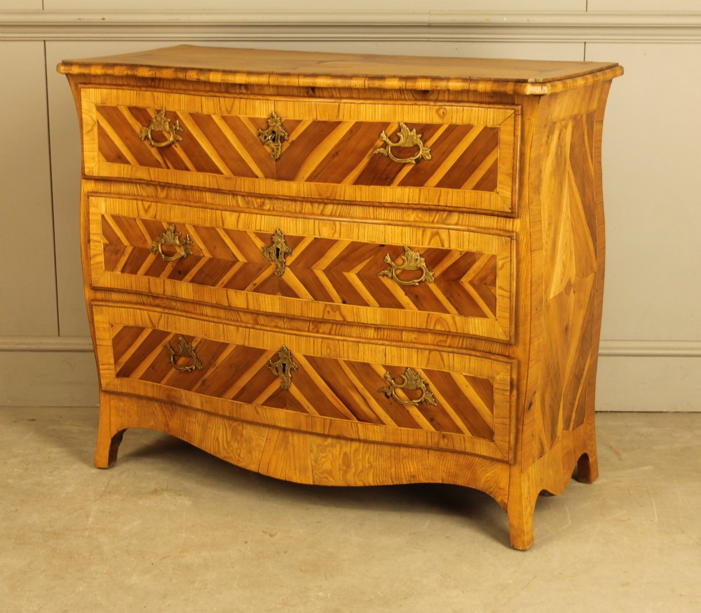 An 18th-century Swedish Rococo bombe chest of drawers featuring geometric chevron parquetry inlays, curved sides, three long drawers, and cast brass hardware. View VIII
