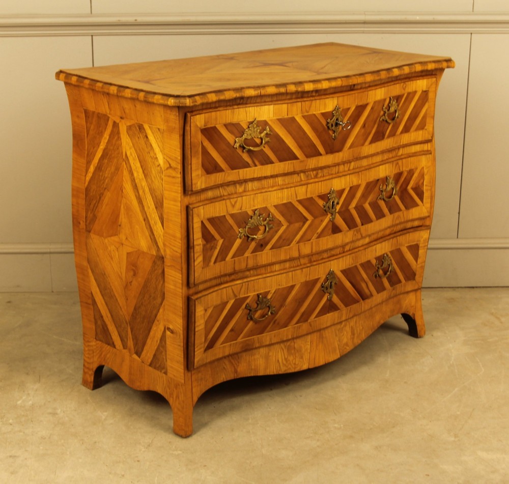 An 18th-century Swedish Rococo bombe chest of drawers featuring geometric chevron parquetry inlays, curved sides, three long drawers, and cast brass hardware. View XI