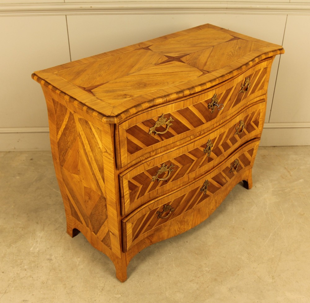 An 18th-century Swedish Rococo bombe chest of drawers featuring geometric chevron parquetry inlays, curved sides, three long drawers, and cast brass hardware. View XII