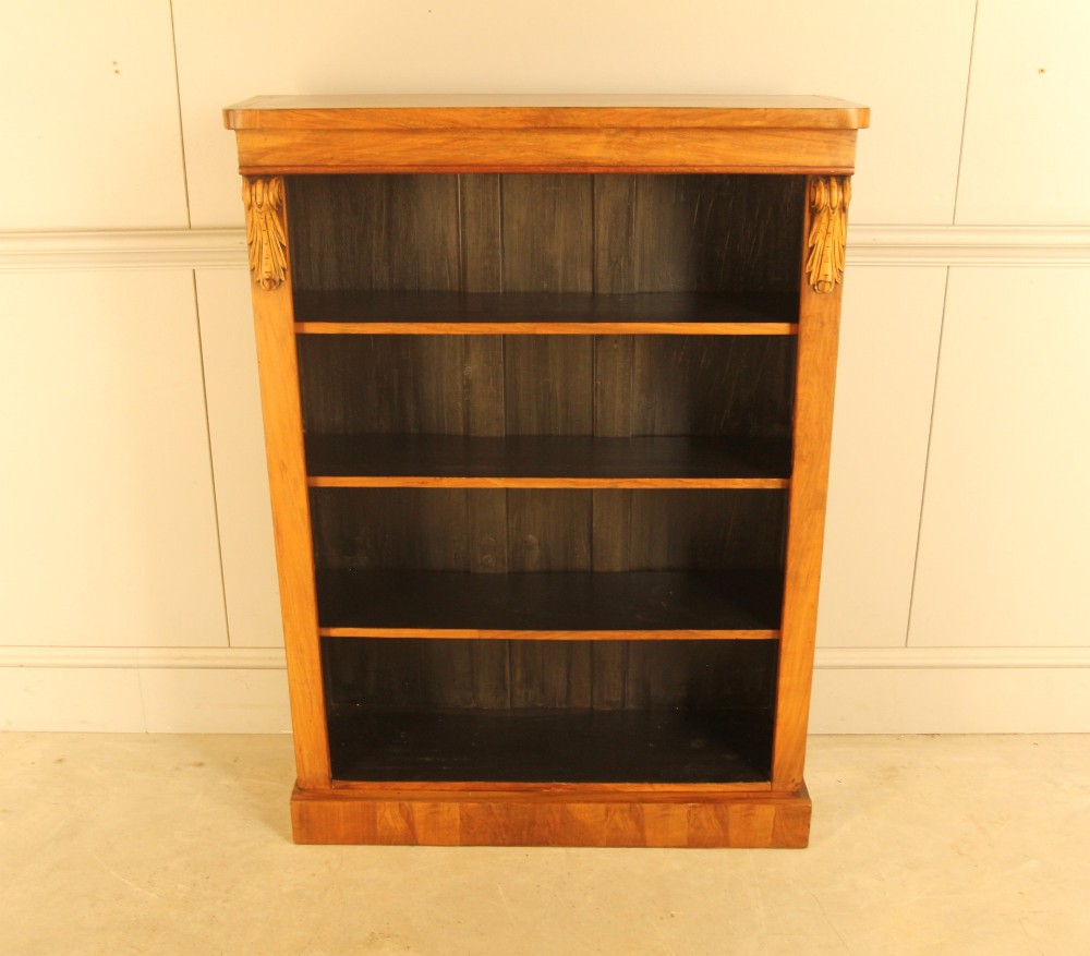 A Victorian walnut open bookcase featuring four horizontal shelves, carved decorative corbels at the upper corners, and a dark painted backboard. View II