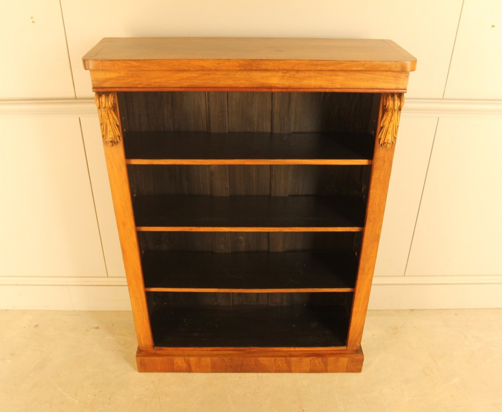 A Victorian walnut open bookcase featuring four horizontal shelves, carved decorative corbels at the upper corners, and a dark painted backboard. View III