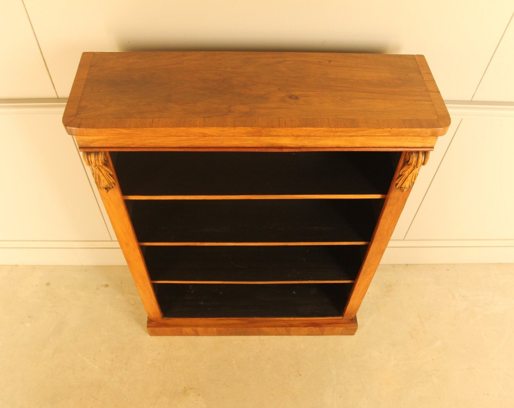 A Victorian walnut open bookcase featuring four horizontal shelves, carved decorative corbels at the upper corners, and a dark painted backboard. View IV
