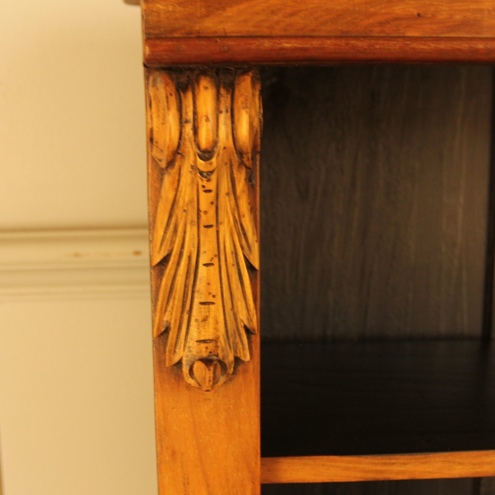 A Victorian walnut open bookcase featuring four horizontal shelves, carved decorative corbels at the upper corners, and a dark painted backboard. View V