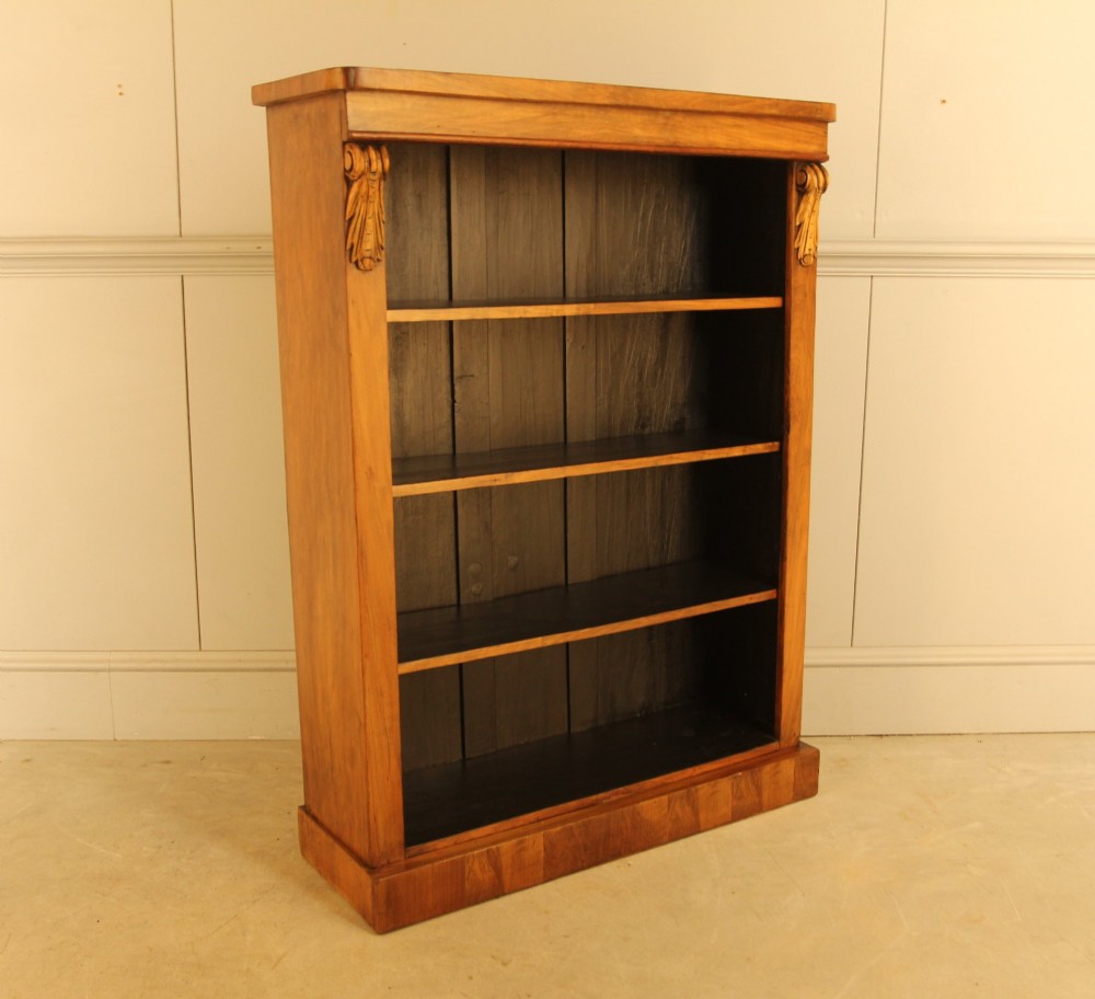 A Victorian walnut open bookcase featuring four horizontal shelves, carved decorative corbels at the upper corners, and a dark painted backboard. View VII