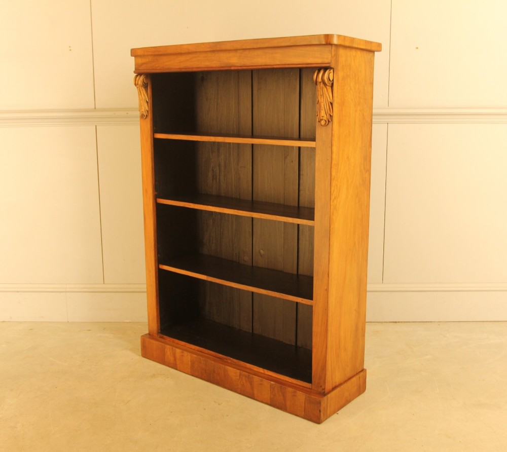 A Victorian walnut open bookcase featuring four horizontal shelves, carved decorative corbels at the upper corners, and a dark painted backboard. View IX
