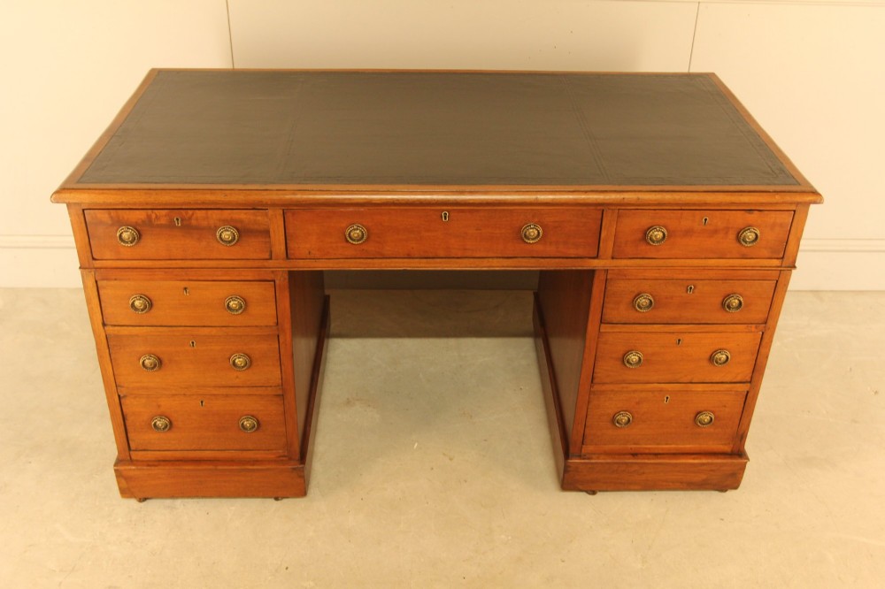 A Victorian walnut pedestal desk featuring nine drawers with brass handles and a dark leather writing inset top. View II