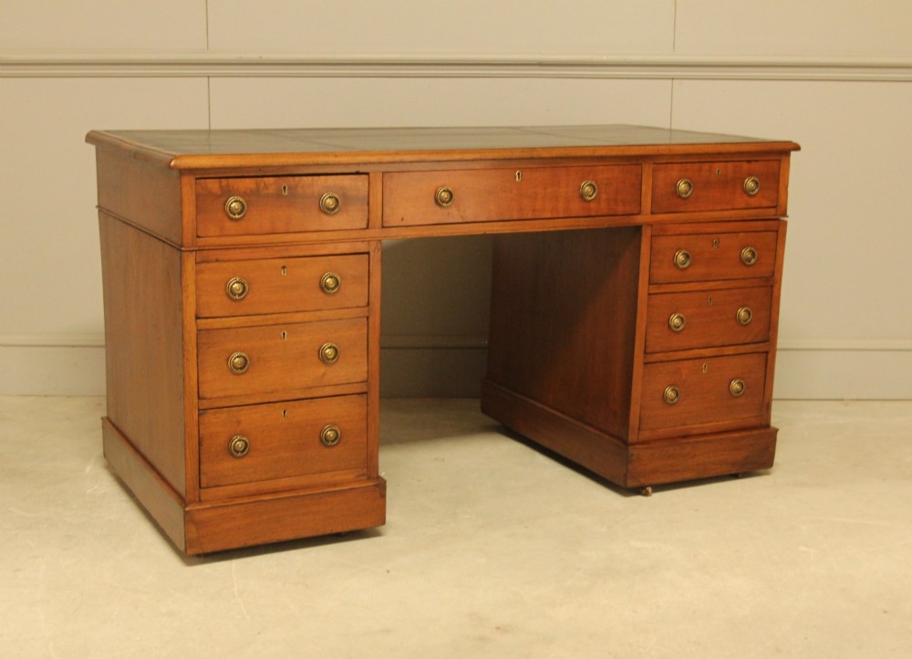 A Victorian walnut pedestal desk featuring nine drawers with brass handles and a dark leather writing inset top. View V