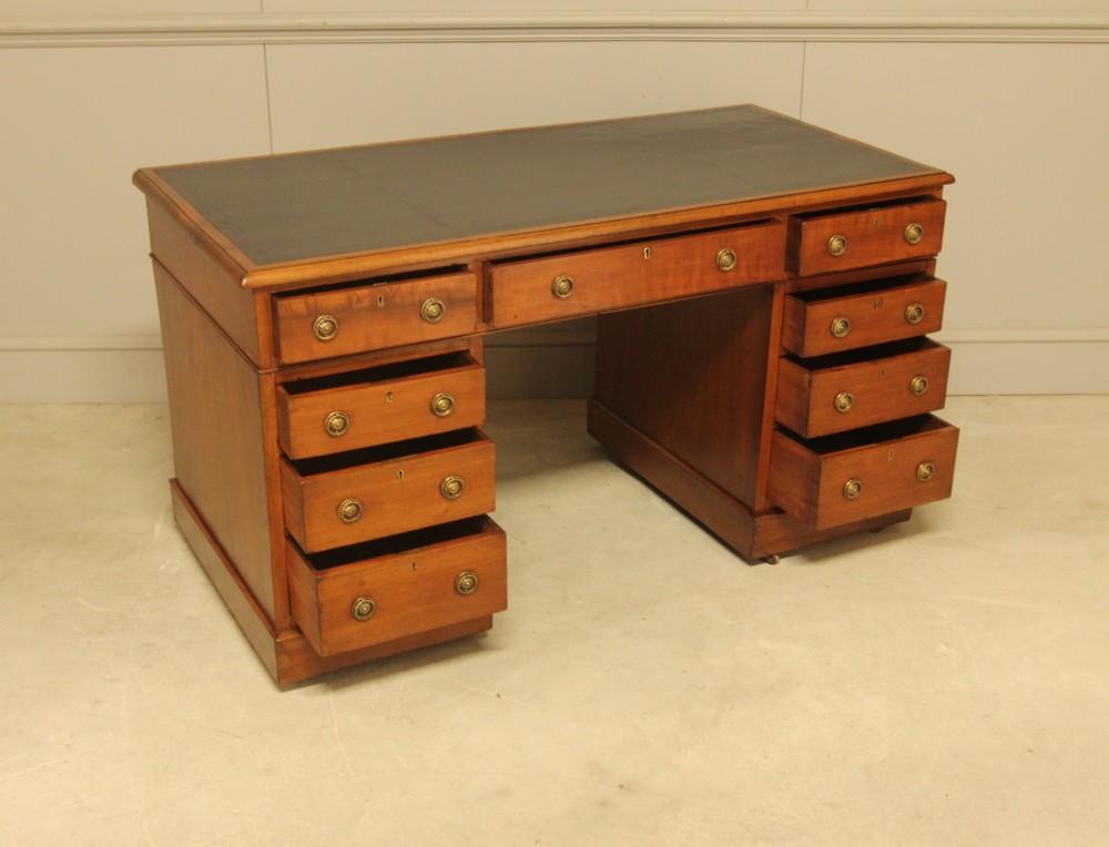 A Victorian walnut pedestal desk featuring nine drawers with brass handles and a dark leather writing inset top. View VI