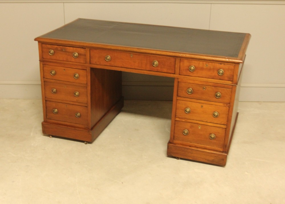A Victorian walnut pedestal desk featuring nine drawers with brass handles and a dark leather writing inset top. View VII