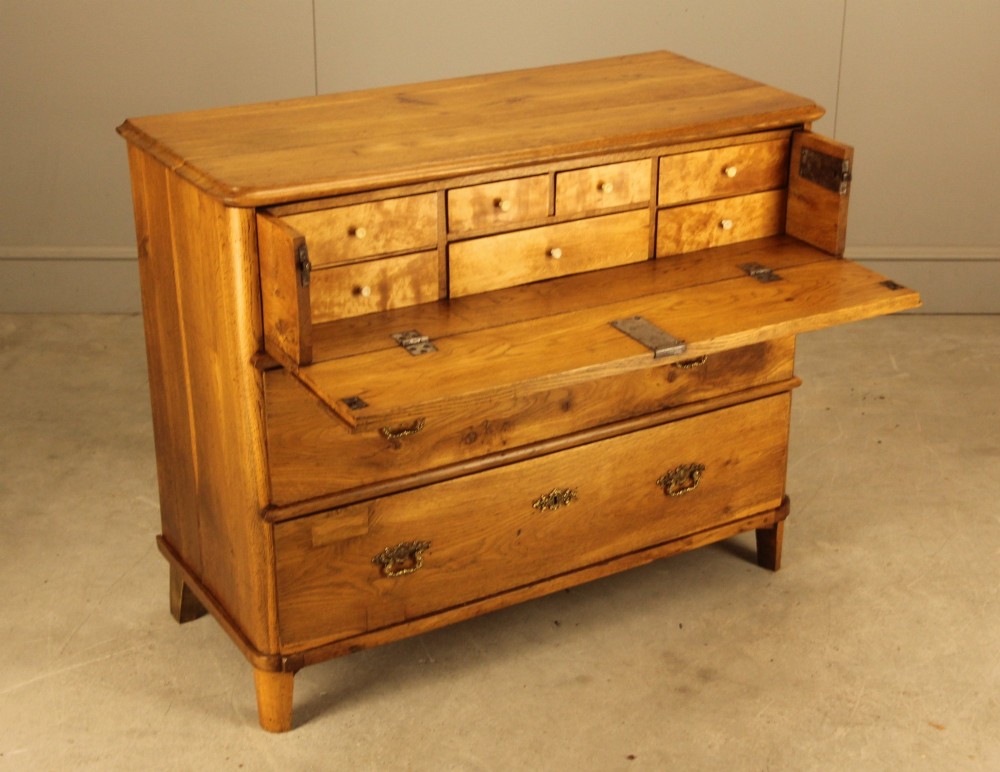 A 19th-century Swedish oak secretaire chest featuring an open hinged fall-front writing flap revealing fitted interior drawers, positioned above two large lower drawers.