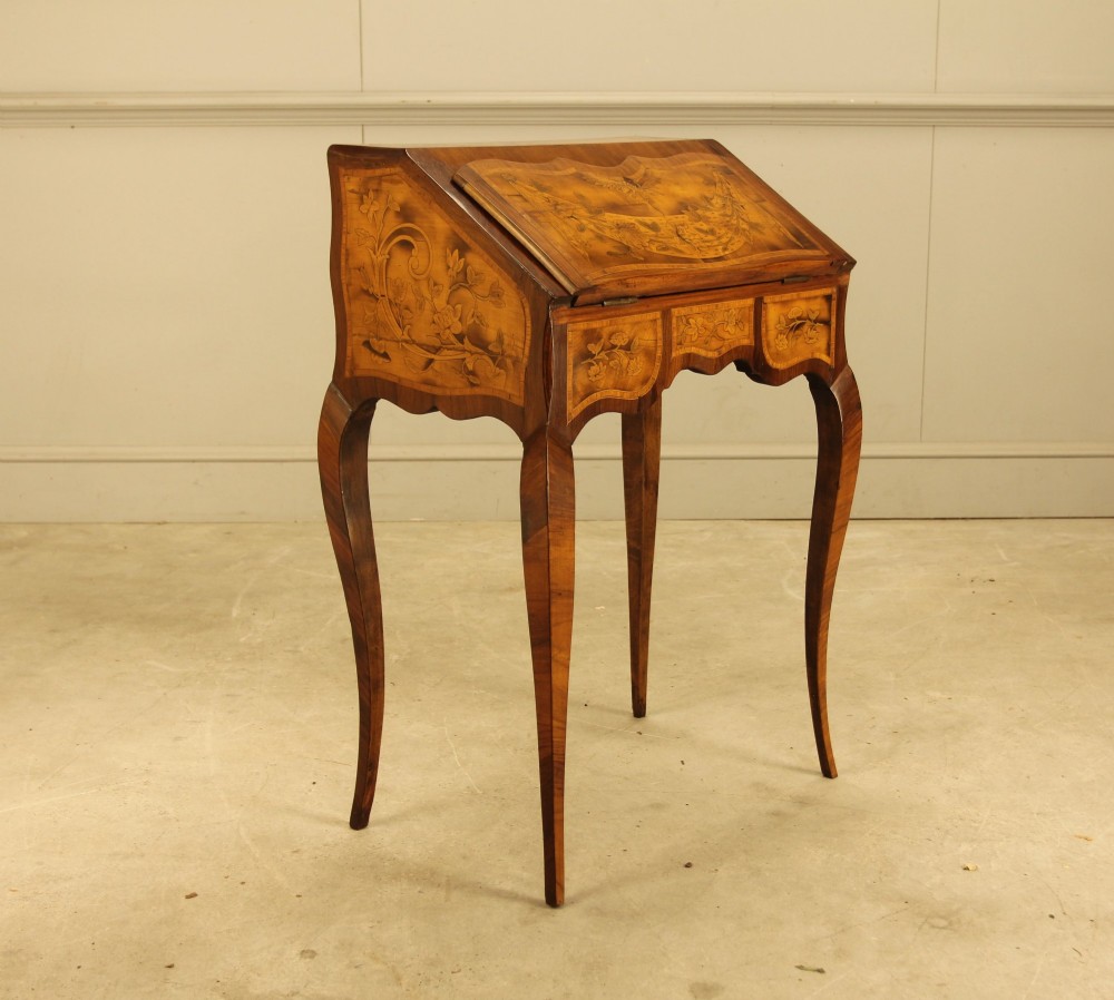 A 19th-century Italian walnut writing bureau featuring floral marquetry inlay, a slanted fall front, and slender cabriole legs.